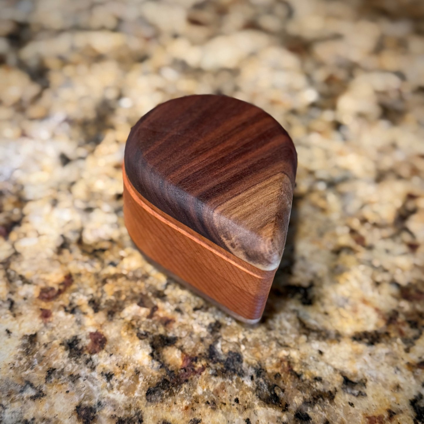 Handmade hardwood salt cellar with fitted lid, shown open on a granite countertop and filled with pink salt. Crafted from contrasting solid woods with a smooth, hand-finished surface.