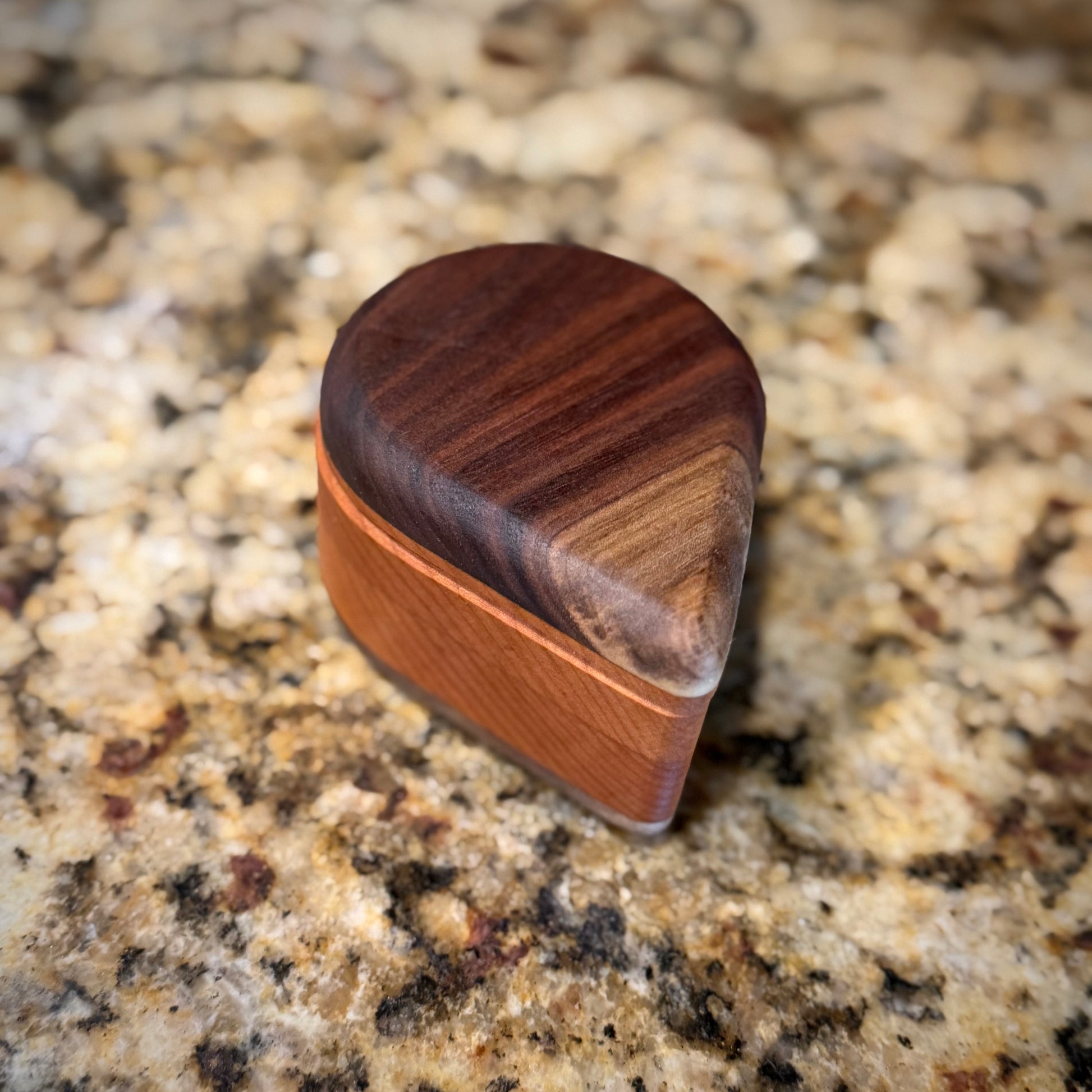 Handmade hardwood salt cellar with fitted lid, shown open on a granite countertop and filled with pink salt. Crafted from contrasting solid woods with a smooth, hand-finished surface.
