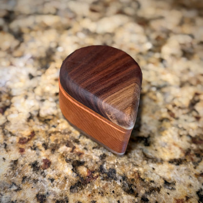Handmade hardwood salt cellar with fitted lid, shown open on a granite countertop and filled with pink salt. Crafted from contrasting solid woods with a smooth, hand-finished surface.