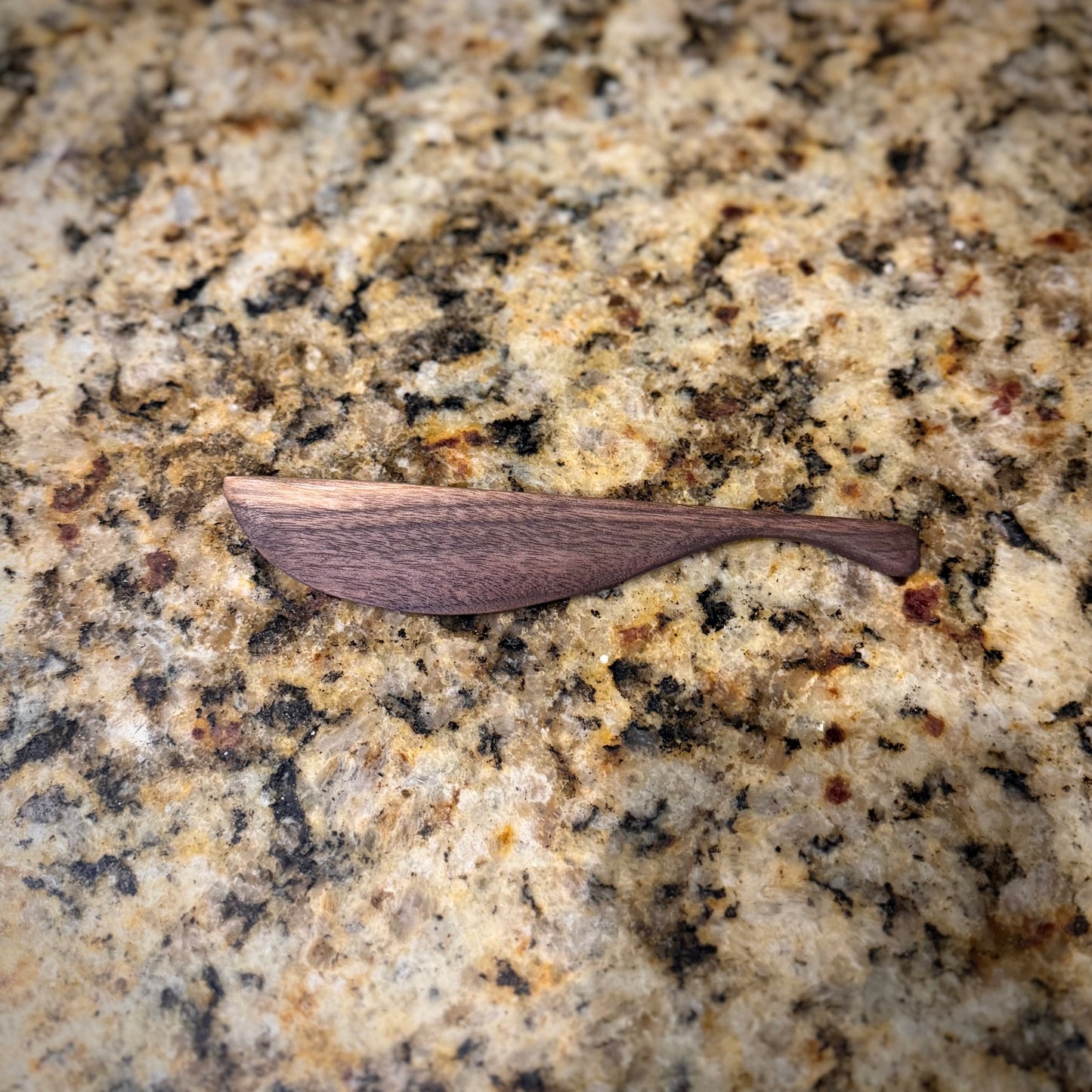 Walnut butter knife in a granite countertop