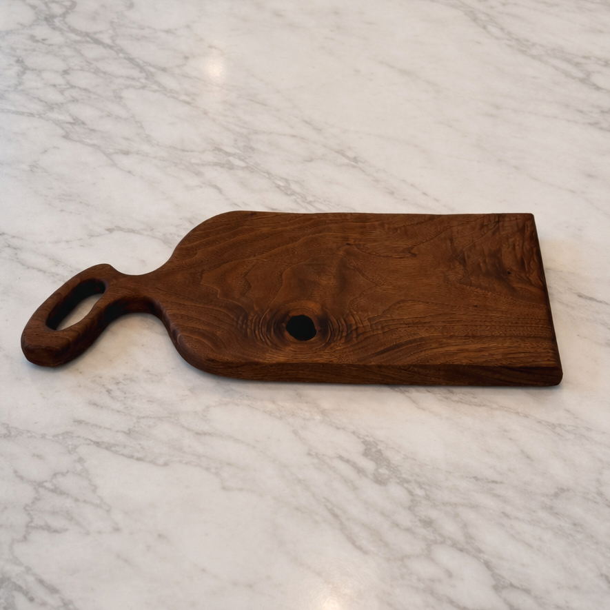 Wooden cutting board with handle on a marble surface