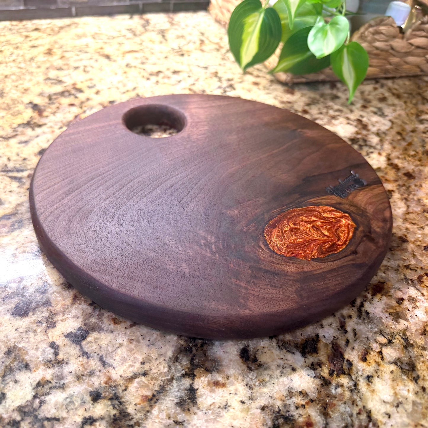 Walnut cutting board with a copper epoxy filled knot on a granite countertop